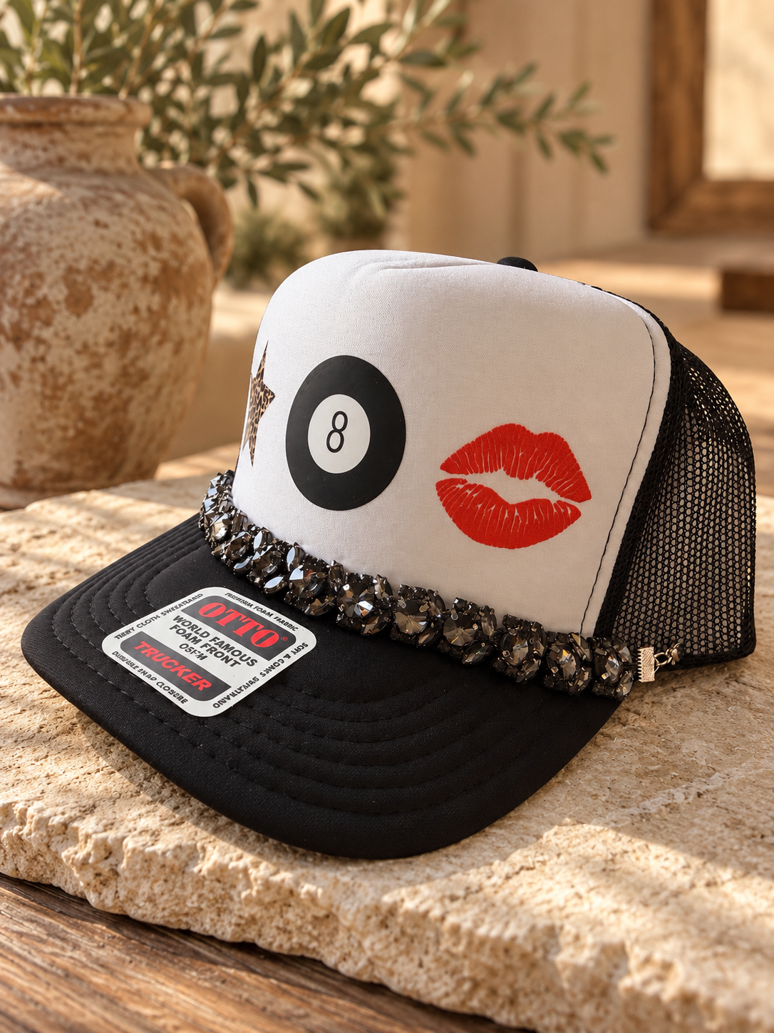 White and black trucker hat with 8-ball, red lips, and rhinestone trim